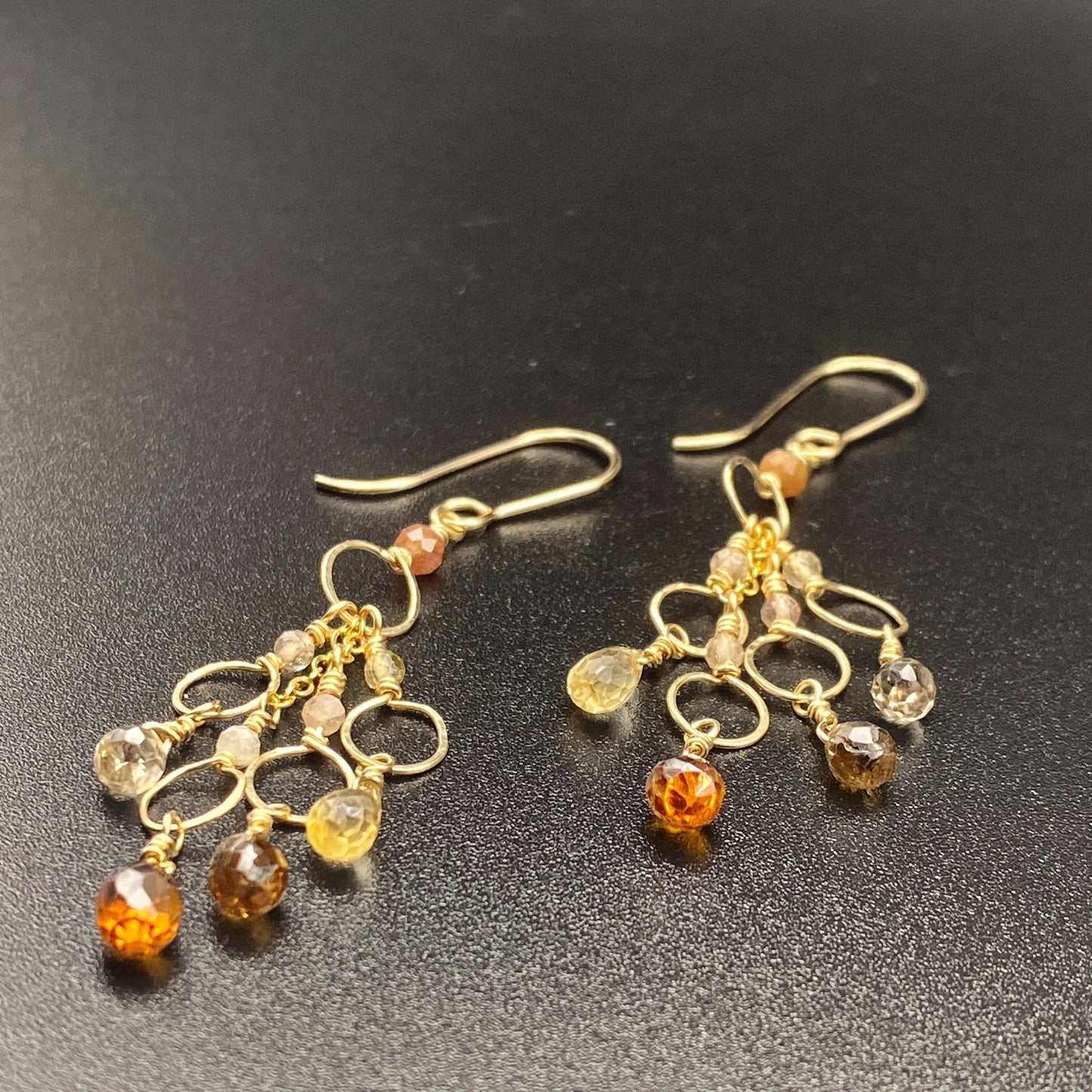 Gold earrings with amber beads on a black background