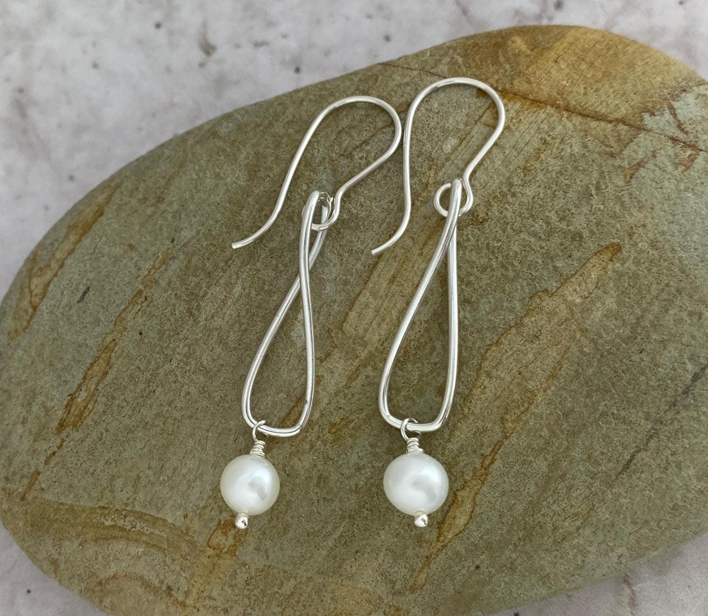 Silver earrings with pearls on a stone surface