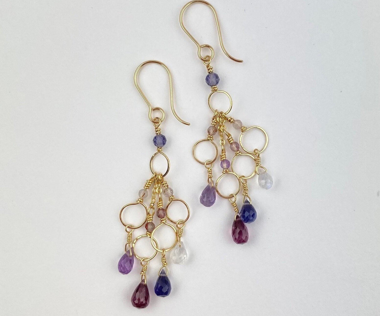 Gold earrings with purple and pink beads on a white background