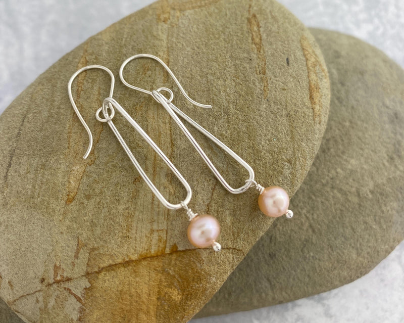 Round pink pearls dangle from twisted silver hoops
