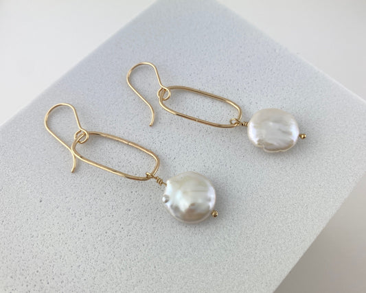 Pair of pearl and gold earrings on a light gray surface