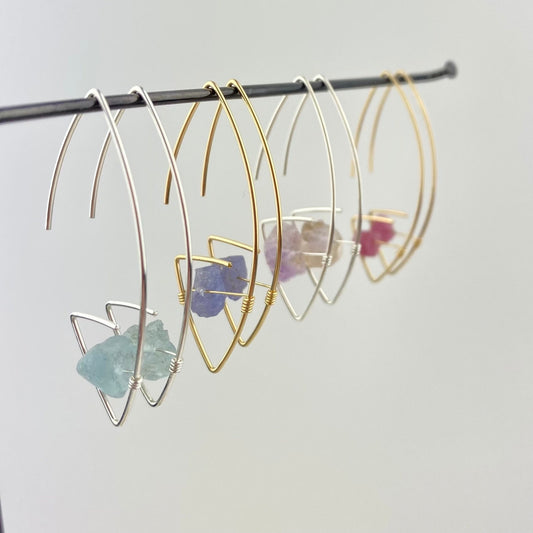 Gold and silver hoop earrings with embedded stones on a gray background