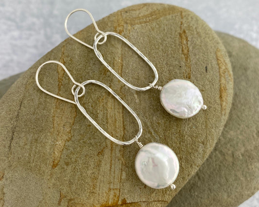 Pearl and sterling silver earrings on a stone surface
