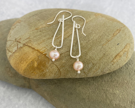 Pink pearl earrings on a stone surface