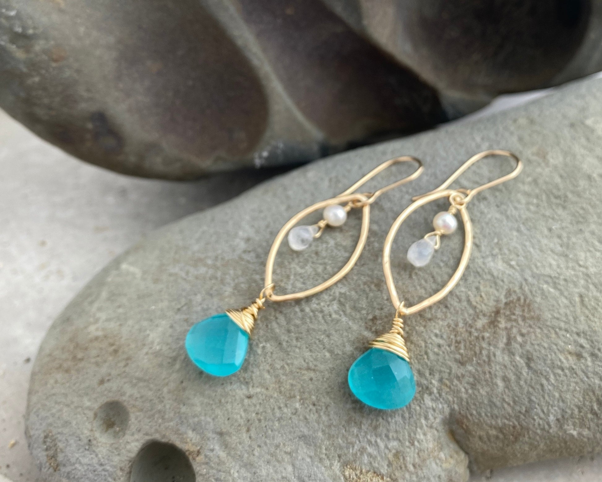 Gold earrings with teal stones on a marquise shaped hoop with moonstone and pearls.
