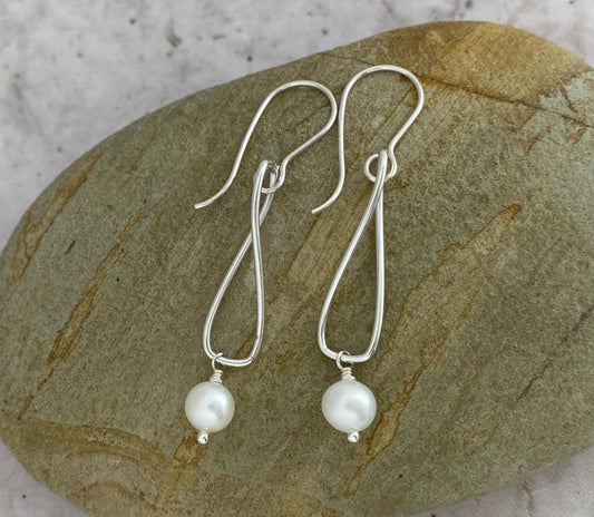 Silver earrings with pearls on a stone surface