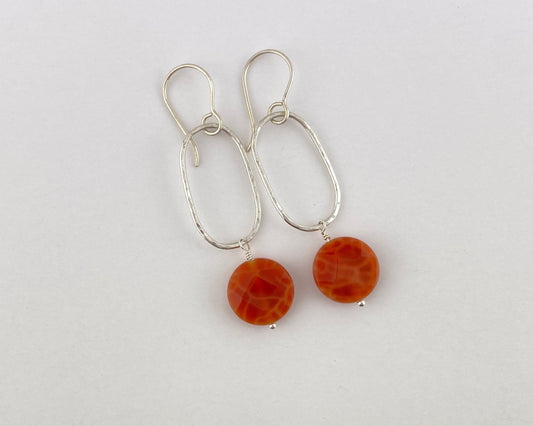 Pair of earrings with orange beads on a light gray background