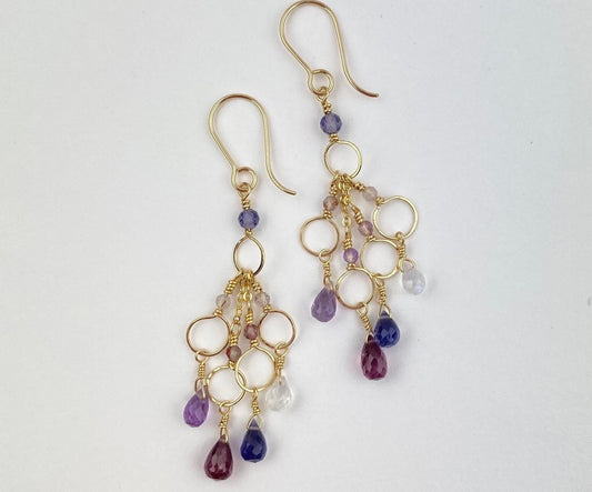 Gold earrings with purple and pink beads on a white background
