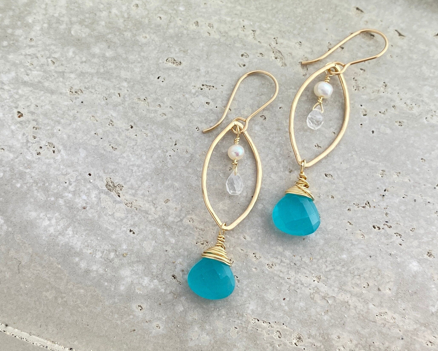 Gold earrings with teal stones on a marquise shaped hoop with moonstone and pearls.